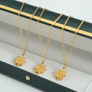 Trois colliers avec pendentifs gouvernail dorés sur un écrin à bijoux vert émeraude
