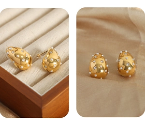 Detail of teardrop gold-plated earrings with pearls and crystals on champagne satin