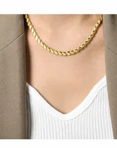 Close-up of a gold wheat chain necklace worn by a model in a minimalist blazer