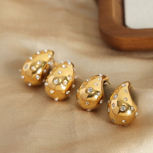Elegant gold teardrop earrings with white pearls and sparkling zircons on silk fabric