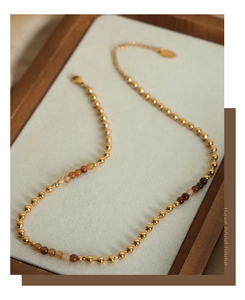 Detalle del collar de cuentas en oro de 18k y piedras naturales en un expositor