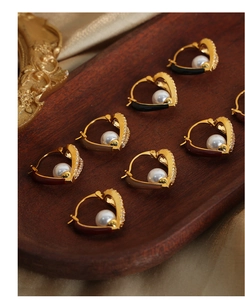 Detail of heart-shaped huggie earrings with pearls and colorful enamel on velvet