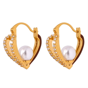 Gold hollow heart earrings with white pearls and sparkling zircons on white backdrop