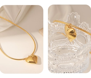 Detail der 18k Gold Herzanhänger Halskette mit Schlangenkette auf elegantem weißem Stoff