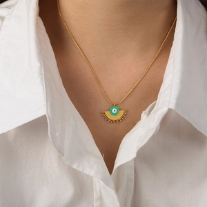 Collar vintage dorado en abanico con dije de ojo turco verde sobre camisa blanca