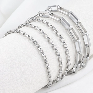Set of five silver stainless steel rectangle and box link chains on a white display stand