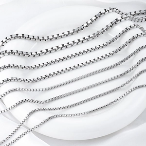 Silver stainless steel box chains in various thicknesses on a white ceramic plate