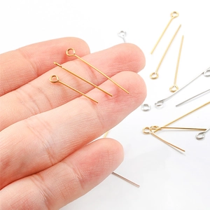 Golden and silver stainless steel eye pins for jewelry making held by hand to show detail