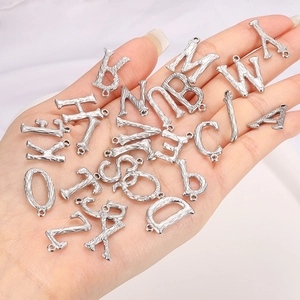 Macro detail of silver stainless steel letter charms with brushed texture for DIY jewelry