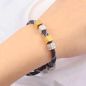 Perline quadrate numerate su bracciale in corda intrecciata con dettagli oro e argento