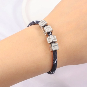Dettaglio bracciale in corda intrecciata con perline quadrate d'argento incise 1996