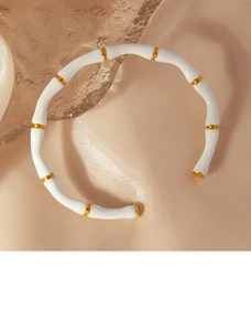 Detail of bamboo-style gold plated bangle with white enamel inlay on champagne silk