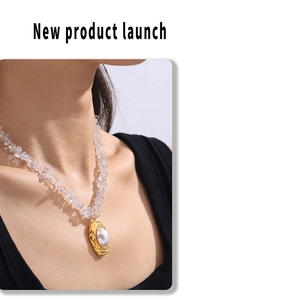 Detail of gold oval pendant with faux pearl and clear crystal beads on a model