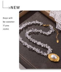 Macro detail of oval gold pendant with white pearl and crystal stone chain necklace