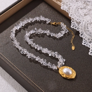 Oval gold plated crystal chip necklace with faux pearl pendant on a jewelry tray