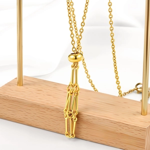 Detail of gold bamboo-style mesh cage chain with geometric fringe pendant and lobster clasp