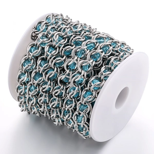 Detailed view of DIY silver metal links with light blue faceted beads on a white spool