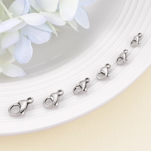 Fermoirs mousquetons en acier inoxydable de tailles variées sur plateau blanc pour bijoux