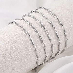Minimalist silver stainless steel geometric chain draped on a white textured display cylinder