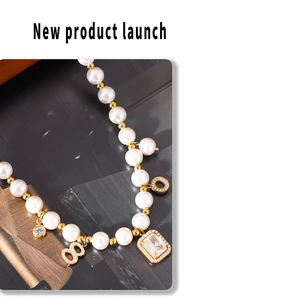 Detailed close-up of pearl necklace with gold charms and large rectangular crystal pendant