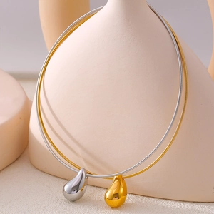 Minimalist gold and silver waterdrop pendant necklaces on ceramic display stand