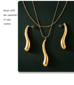 Détail d'un ensemble de bijoux dorés avec pendentifs gouttes sur cuir vert