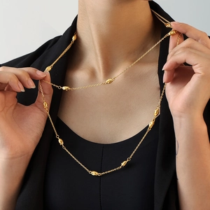 Elegante gouden dubbellaagse titaniumstalen truiketting met ovale kralen op een model