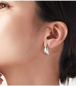 Close-up of a silver geometric triangular earring on model for minimalist daily style