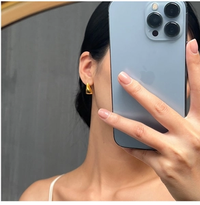 Close-up of geometric triangle titanium steel earrings with a polished gold finish