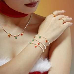 Weihnachtliches Perlen-Schmuckset mit Emaille-Anhängern, von Model getragen vor warmem Hintergrund