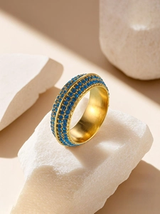Dettaglio macro di anello placcato oro con tre file di zirconi blu incastonati