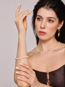 Dettaglio del bracciale di perle barocche irregolari con orecchini a goccia dorati eleganti