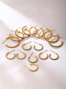 Detailed view of C-shaped titanium steel earrings with vibrant cubic zirconia inlays