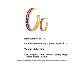 Detailed view of gold C-shaped stainless steel earrings with red and blue zircon inlay