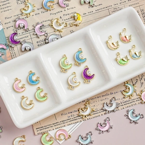 Bunte Mondsichel-Anhänger mit Sternen und Perlen auf weißem Tablett für DIY-Schmuck