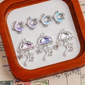 Moon and jellyfish alloy pendants with iridescent crystals in a wooden display tray