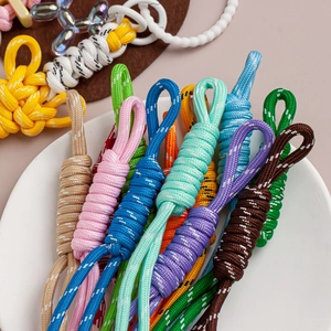 Detailed close-up of colorful nylon knotted cords for keychains in a white ceramic dish
