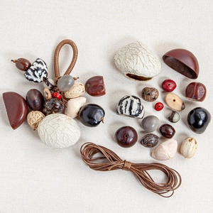 Flat lay of natural plant seeds and cord for DIY jewelry making on linen background