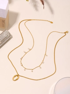 Dettaglio di una collana a strati placcata oro con perle delicate e ciondolo ovale