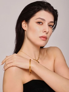 Model wearing a polished 18K gold plated minimalist bangle and delicate pendant necklace