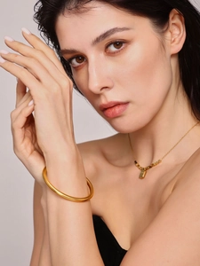 Polished 18K gold-plated hollow bangle and beaded necklace on female model neck