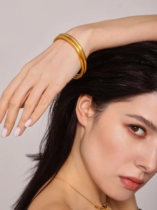 Detail view of double-layered gold matte finish bangle on model wrist with minimalist style