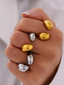 Macro shot of minimalist gold and silver teardrop rings featuring polished PVD finish