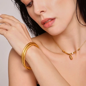 Minimalist gold-plated stainless steel cuff bracelet and geometric necklace on model