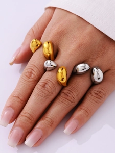 Close-up of teardrop minimalist rings in gold and silver finish with high-polish texture