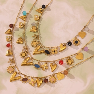 Golden multi-element layered necklaces with colorful heart and floral charms on marble background