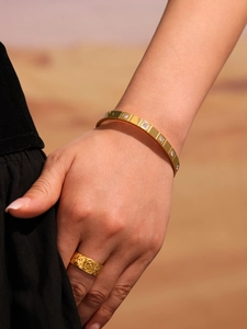 Close-up of a 18K gold plated bracelet with square CZ stones and a textured band ring
