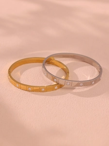 Detail of gold and silver stainless steel bangles with cubic zirconia inlays and shadows