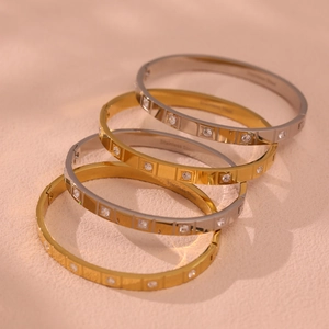 Luxury stainless steel bangle with CZ stones in gold and silver finish on pink leather