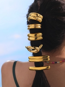Detailed back view of gold-plated hair ties and clips on a ponytail against a blue sky